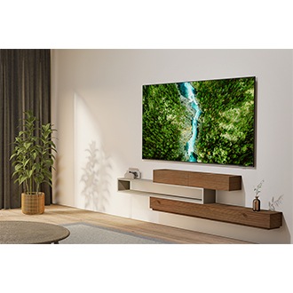 A U8000F is installed on the wall of a living room. The screen displays a top-down view of a lush forest and a flowing river.