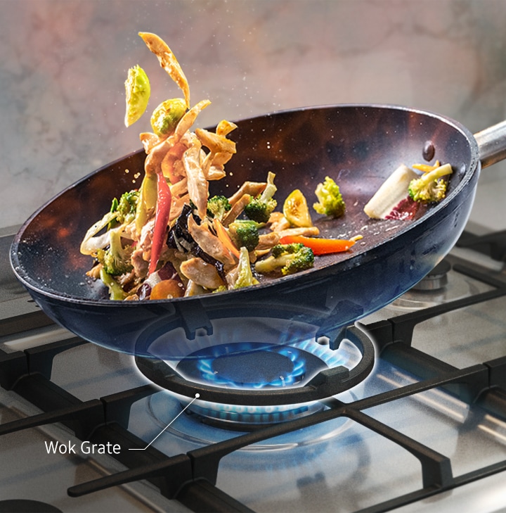 Stir-fried food is being prepared in a wok above the circular Wok Grate.