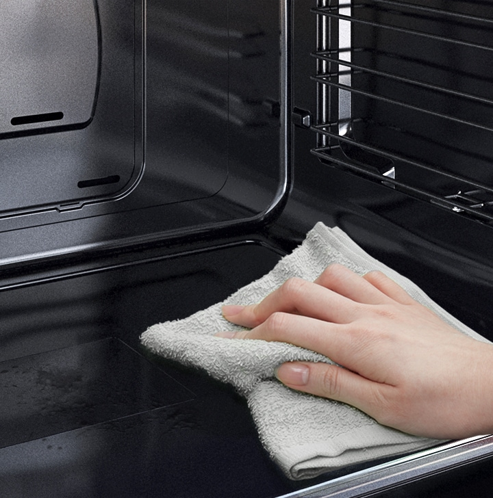 A person is wiping down the oven’s Easy Clean surface using just a cloth.