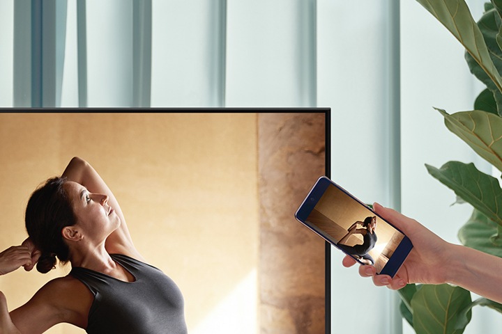 A user taps their smartphone against their AU8000 TV to mirror their ballerina contents to a bigger screen for more comfort.