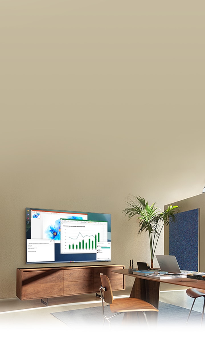 In a living room home office, QLED TV screen shows PC on TV feature which allows home TV to connect to office PC.