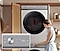 A white Bespoke Grande AI washer and dryer set is stacked vertically in a cabinet that has a wooden door with shutters. A woman is touching the knob on the washer, demonstrating the machine’s All-in-one Control function. There is a closeup of the knob, with a display located to its right. The washer has been selected and the text AI Wash and the number 40 is on the display.