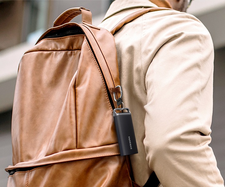 Someone wearing a sand-colored backpack. The T5 EVO is conveniently clipped to the side of the backpack, highlighting its portable design.