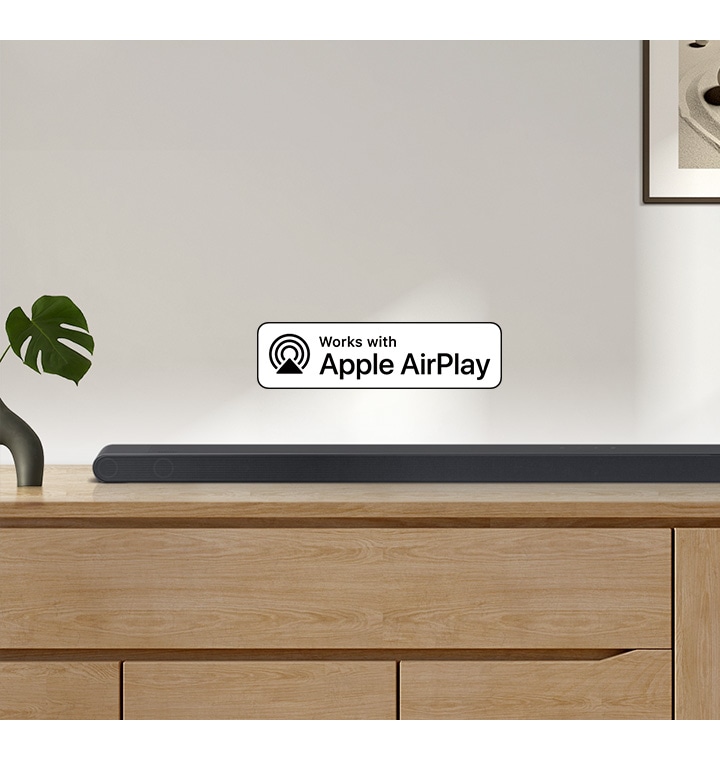 A Samsung Soundbar sits on top of a cabinet, accompanied by a logo for Works with Apple AirPlay.