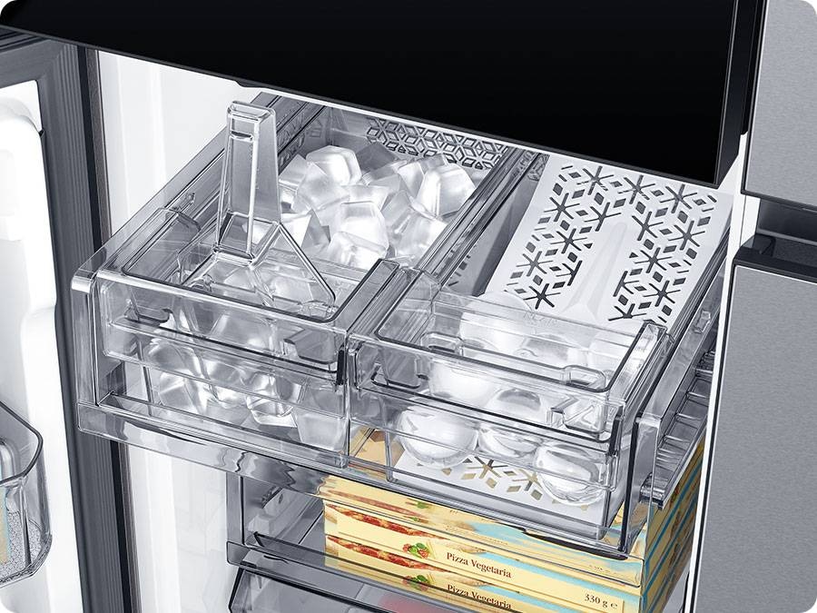 The dual tray in the freezer has ice. The left tray is full of cubed ice and the right tray has whiskey ball ice.