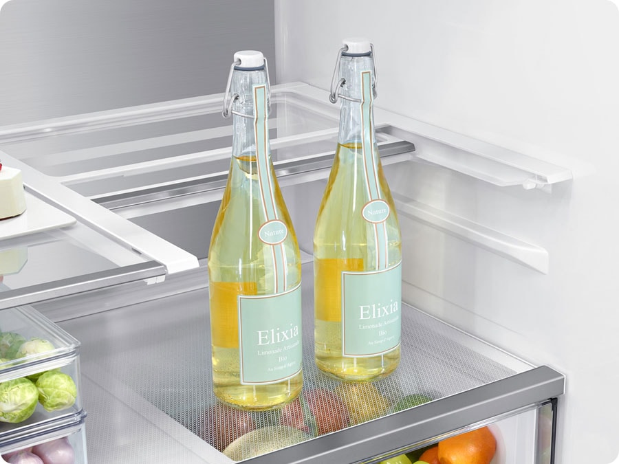 There is a closeup of a folded slide-in shelf inside the refrigerator. There are two tall glass bottles.