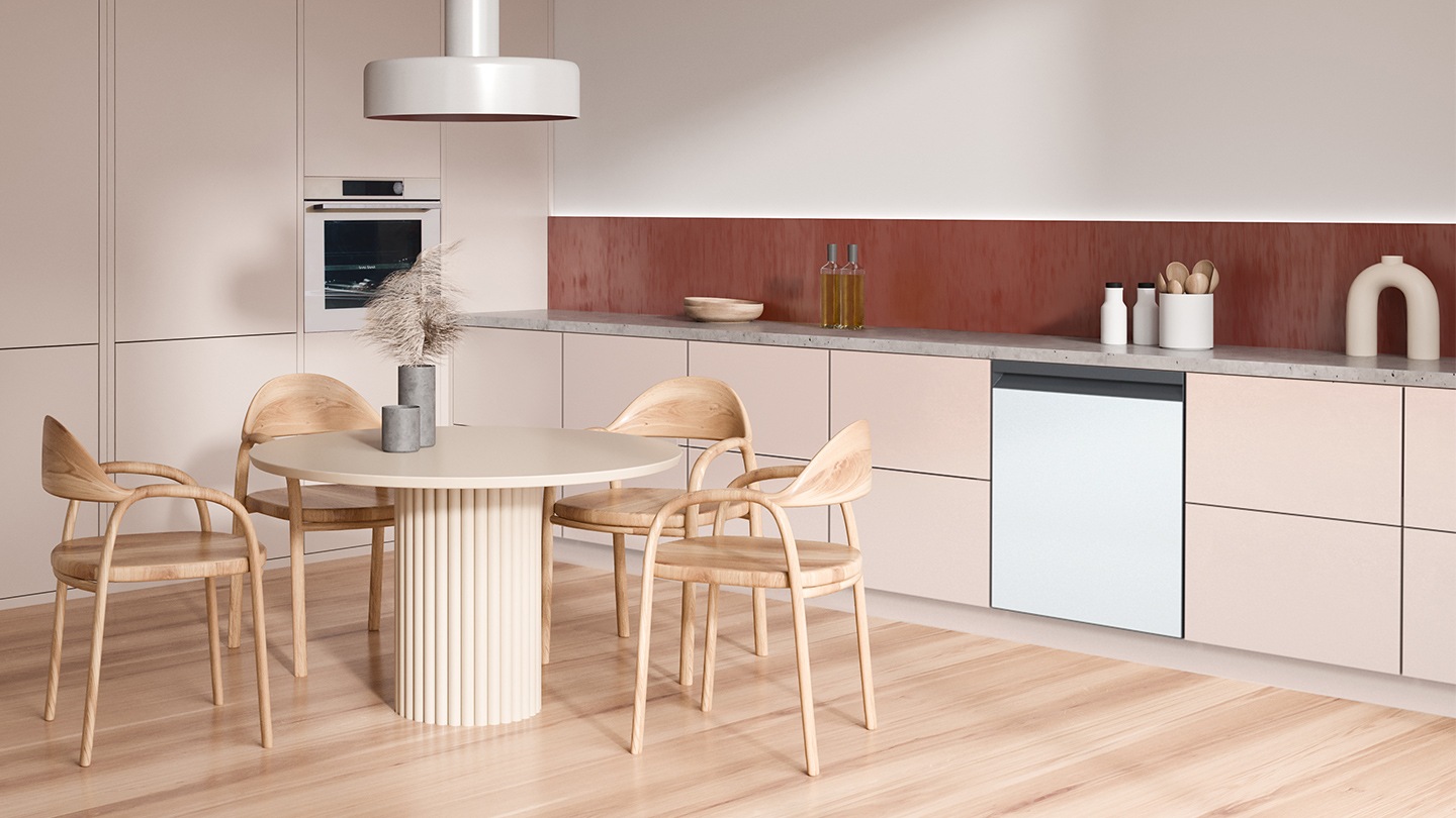 Shows the dishwasher with a white door panel that complements the pale pink and natural wood colored design of the kitchen cabinets, table and chairs and flooring.