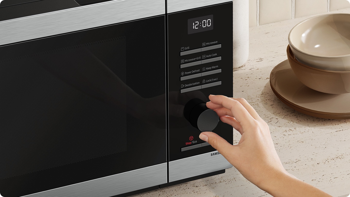 A person is turning the dial on the microwave and controlling it.