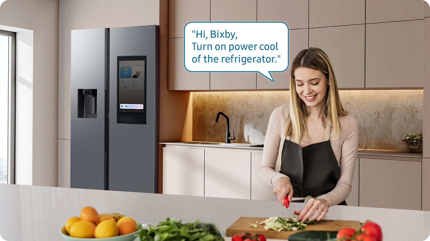 Shows a person preparing food while controlling the refrigerator using a Samsung Bixby. “Hi Bixby, Please update the status of other devices.”