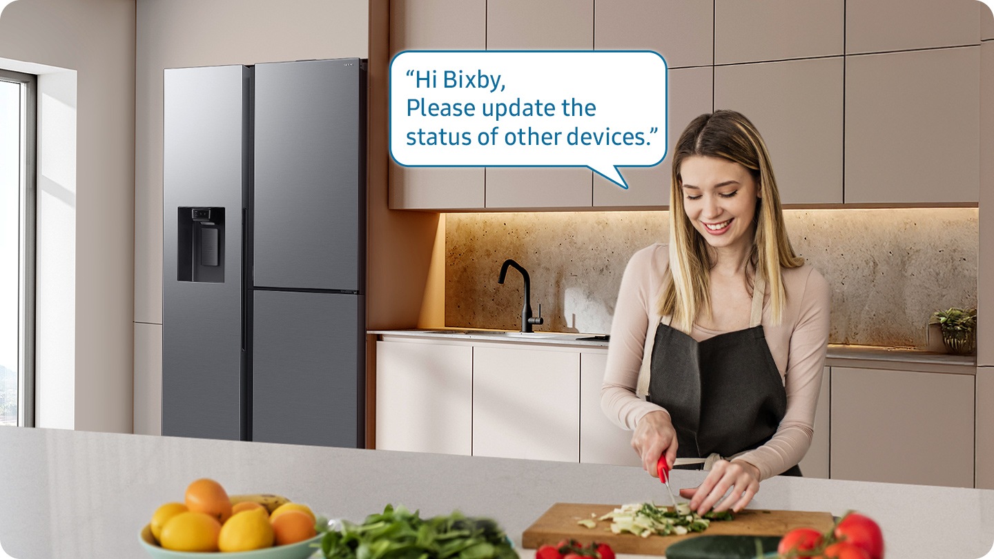 Shows a person preparing food while controlling the refrigerator using a Samsung Bixby. “Hi Bixby, Please update the status of other devices.”