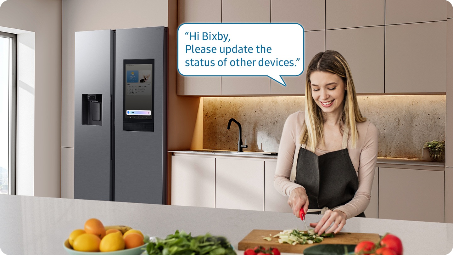 Shows a person preparing food while controlling the refrigerator using a Samsung Bixby. “Hi Bixby, Please update the status of other devices.”