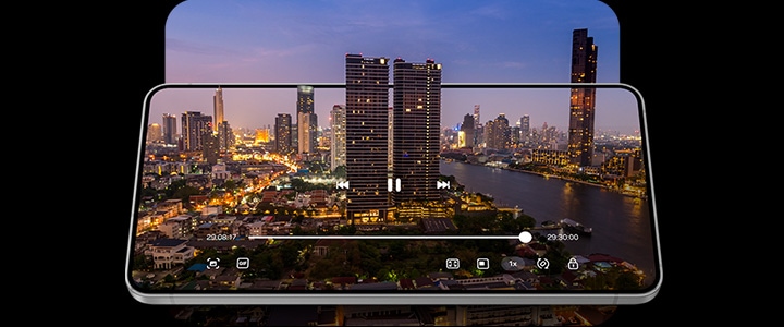Galaxy S25 Edge seen laying almost flat, with a video of a city skyline at dusk in the background to demonstrate all-day battery life.
