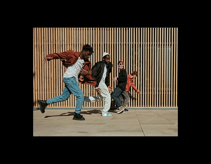 A photo of four men running in front of a wood-panel wall is clear, vibrant and full of detail.