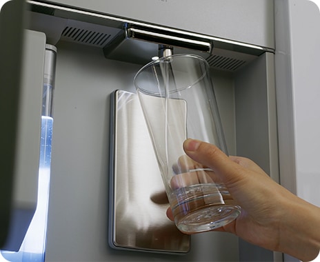 Beverage Center’s Autofill Pitcher is next to the Water Dispenser, which has a Washable Nozzle that pours water into a cup.