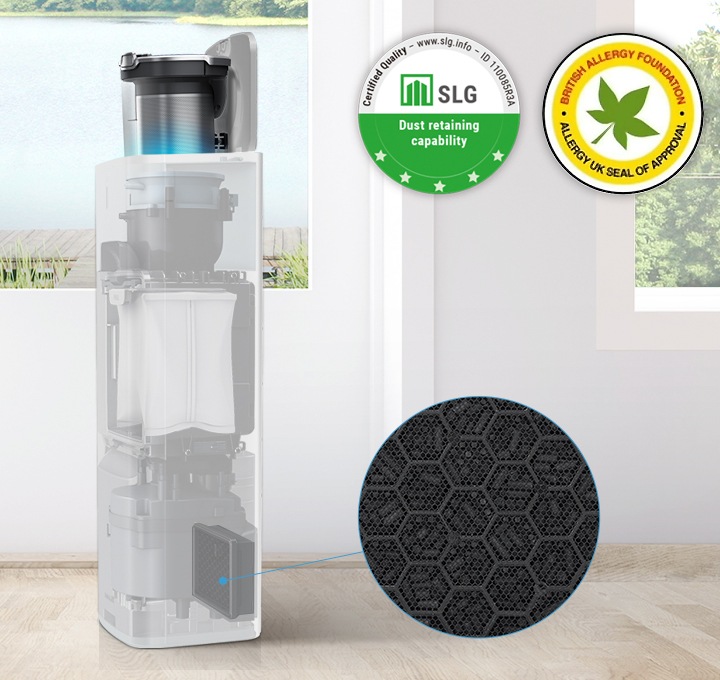 원목 마루가 깔린 거실 뒤에는 하얀 벽이 있고 벽 가운데와 오른쪽에는 호수가 보이는 창문이 있습니다. 창문 가장 왼쪽에는 흰색의 얇은 커튼이 드리워져 있습니다. 이미지 왼쪽 하단에는 원형 테이블이 보이고 이미지 가장 가운데 청정스테이션에 먼지통이 결합되어 있는 모습이 보입니다. 청정스테이션 내부는 투명하게 처리되어 안 쪽 내부 부품이 투명하게 보이는 상태로 가장 하단 청정스테이션용 배기필터 부분을 파란색 선으로 표시 후 확대하여 보여주소 있습니다. 이미지 오른쪽 상단에는 SLG 인증 로고와 BAF 인증 로고가 나란히 나열되어 있습니다.