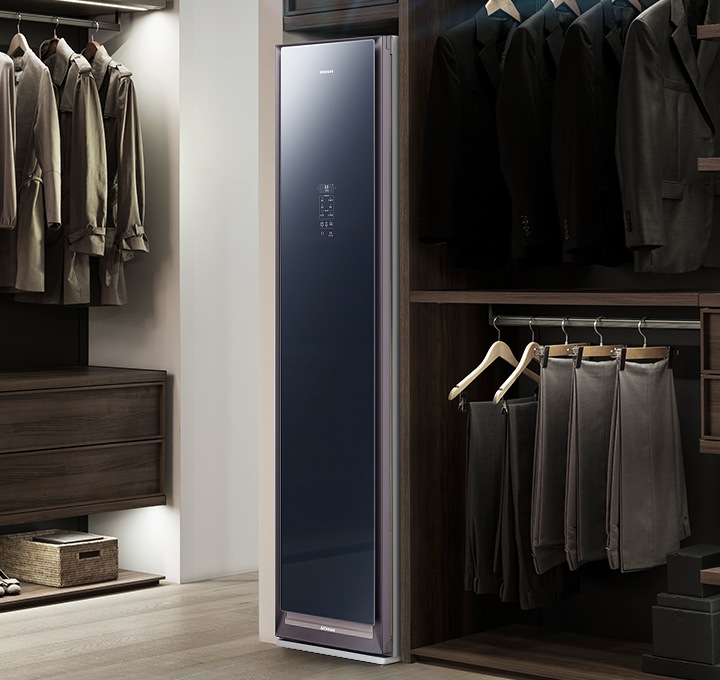 드레스룸의 원목 재질의 의류장에 빌트인 형식으로 설치되어 제습기능이 작동 중인 에어드레서 제품이 보입니다.