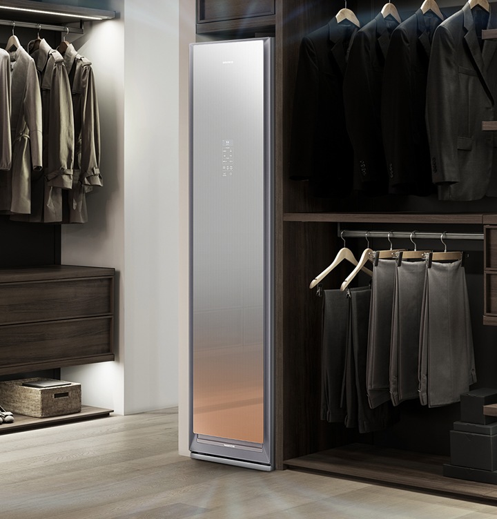 드레스룸의 원목 재질의 의류장에 빌트인 형식으로 설치되어 제습기능이 작동 중인 에어드레서 제품이 보입니다.