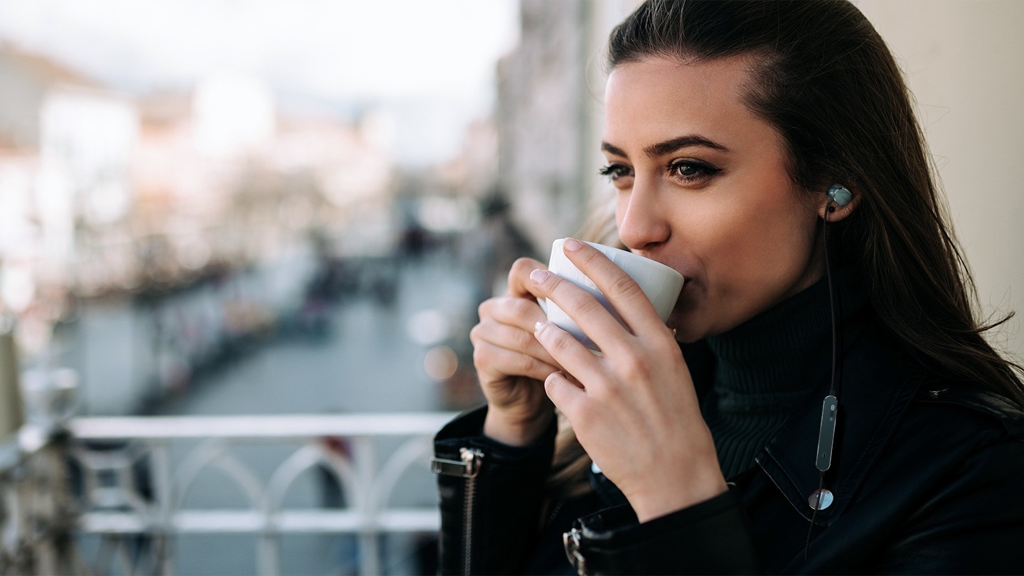 한 여자가 이어폰을 착용하고 있는 옆모습이 확대 되어 보입니다. 