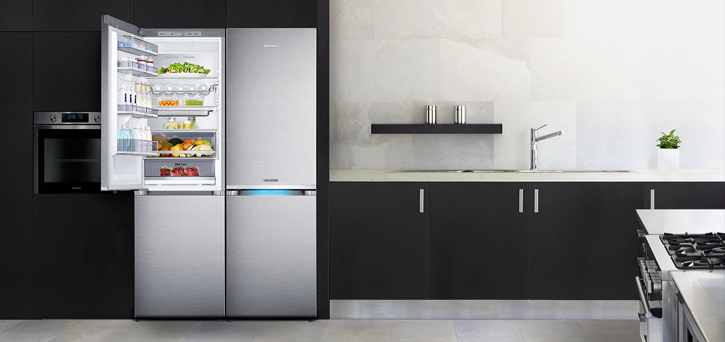 블랙/화이트톤 인테리어컷으로 오른쪽에 싱크대와 화구가 있는 인테리어컷 입니다. 왼쪽에는 블랙 컬러 냉장고장에 셰프 컬렉션 빌트인 냉장고 2대가 설치되어 있습니다. 2대의 냉장고 중 왼쪽 냉장고 상칸 도어가 오픈되어 있고 안에 음료와 각종 과일 및 식재료가 가득 차 있습니다.
