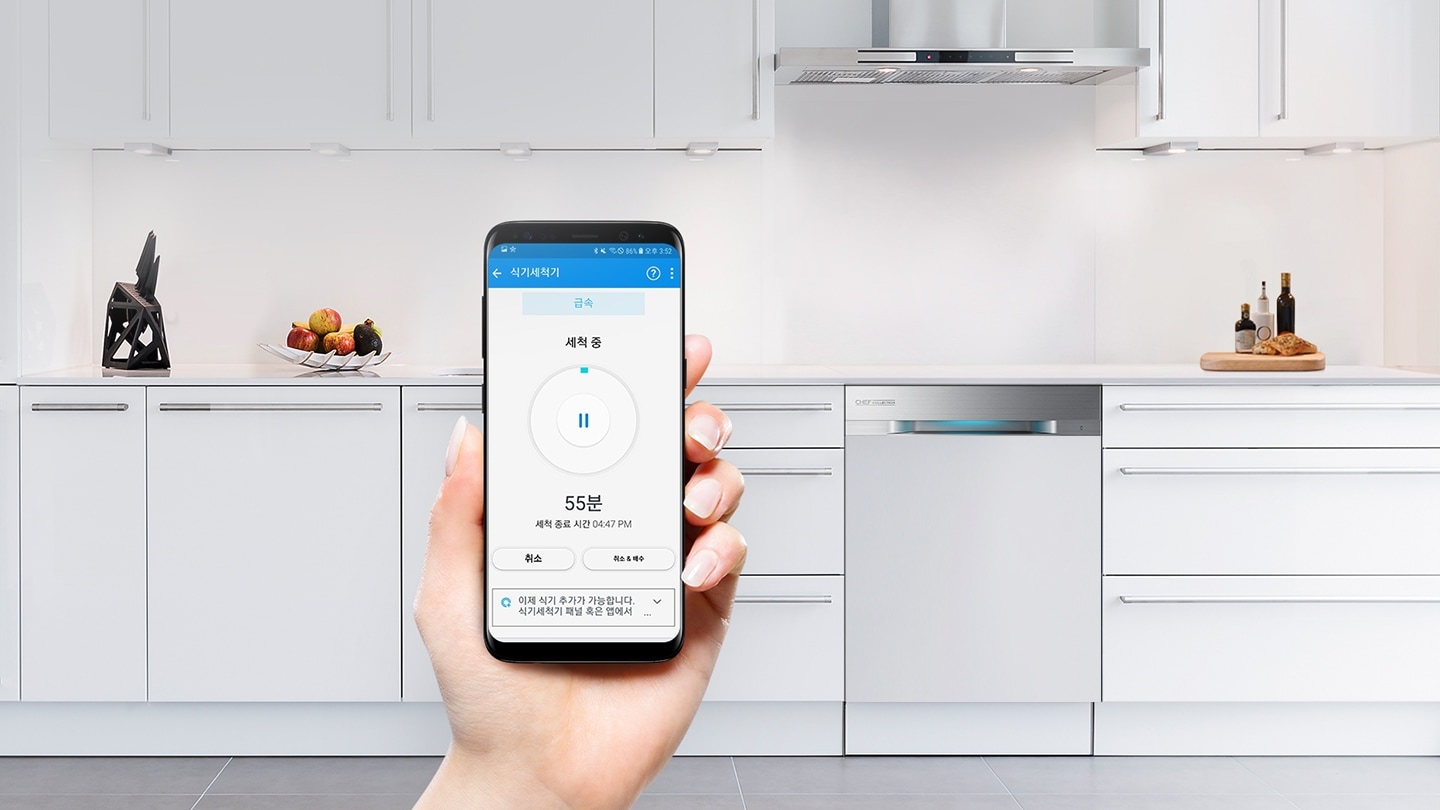 주방에 식기세척기가 있으며, 스마트폰을 사용하여 어플리케이션이 실행되고 있습니다,
