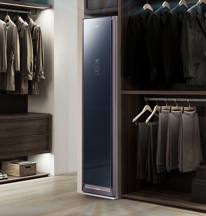 드레스룸의 원목 재질의 의류장에 빌트인 형식으로 설치되어 제습기능이 작동 중인 에어드레서 제품이 보입니다.