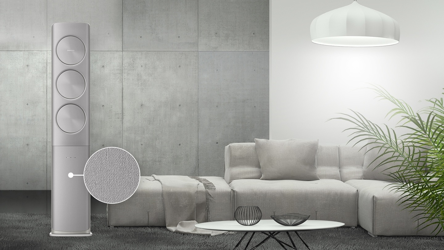 그레이 톤 거실에 조화롭게 놓여진 무풍에어컨이 보여지며, 에어컨 하단 판넬의 그레이 톤 패브릭 패턴을 확대하여 보여주고 있습니다.