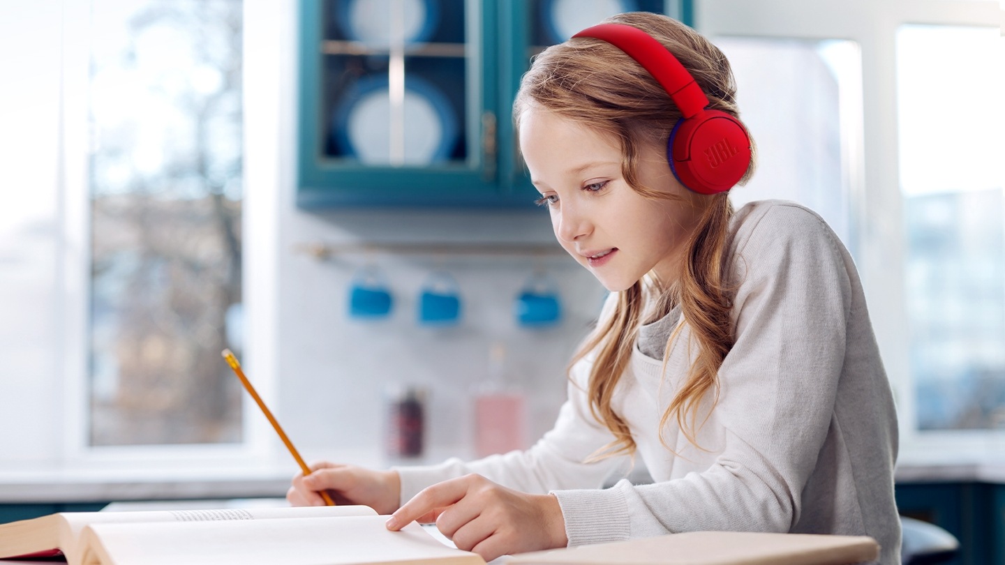 헤드폰을 쓴 여자아이가 레드색상 헤드폰을 쓰고 공부를 하고 있습니다.
