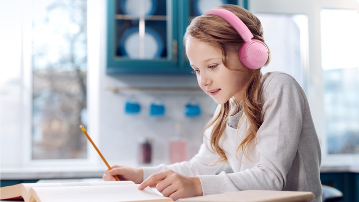 여자 아이가 핑크색 헤드폰을 쓰고 공부를 하고 있는 모습이 보입니다.