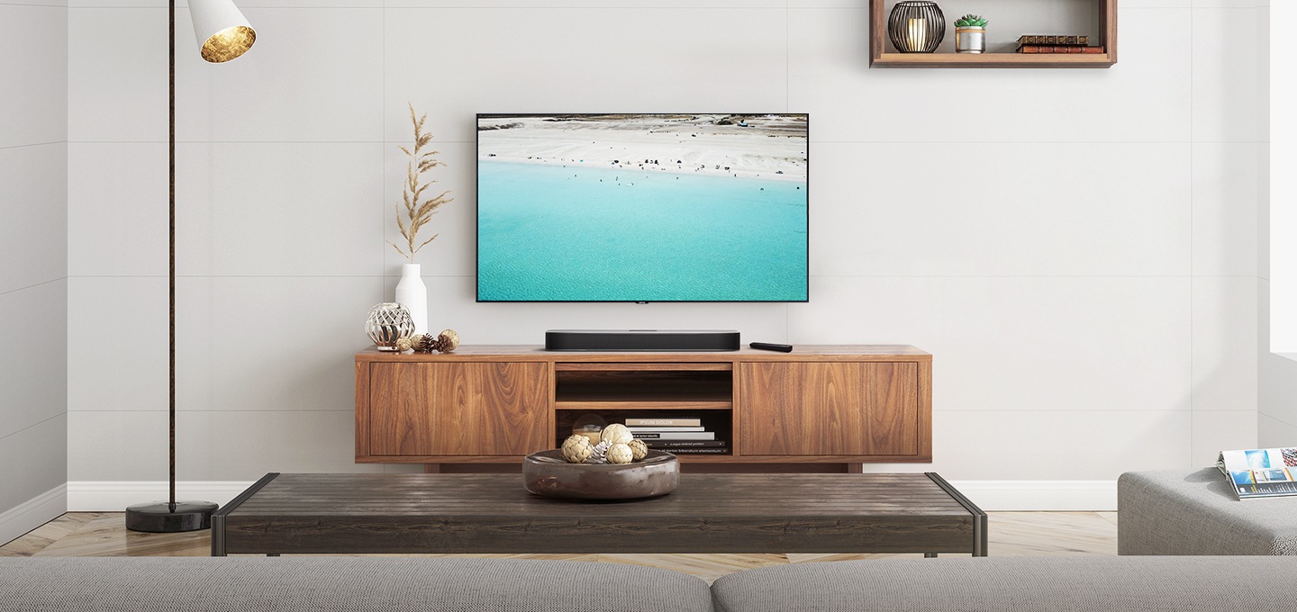 인테리어가 깔끔한 거실에 사운드바와 벽걸이 TV가 설치되어 있습니다.