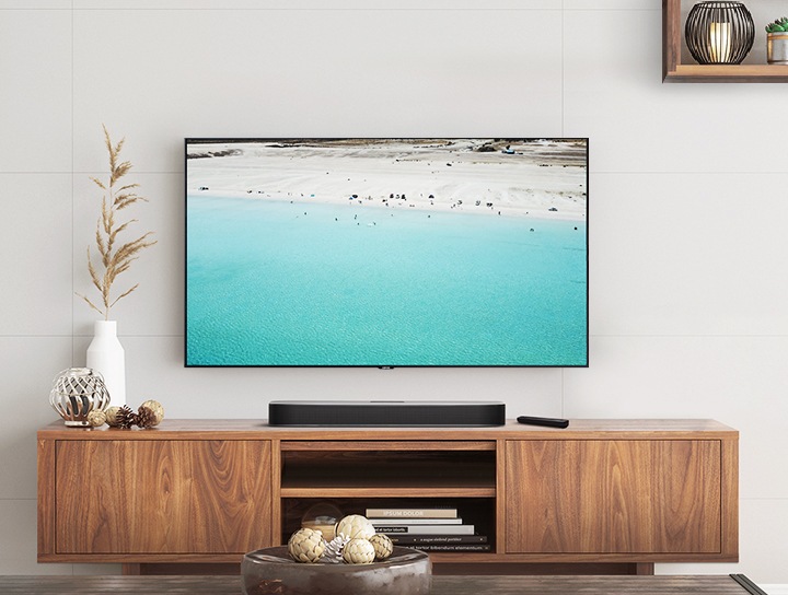 인테리어가 깔끔한 거실에 사운드바와 벽걸이 TV가 설치되어 있습니다.