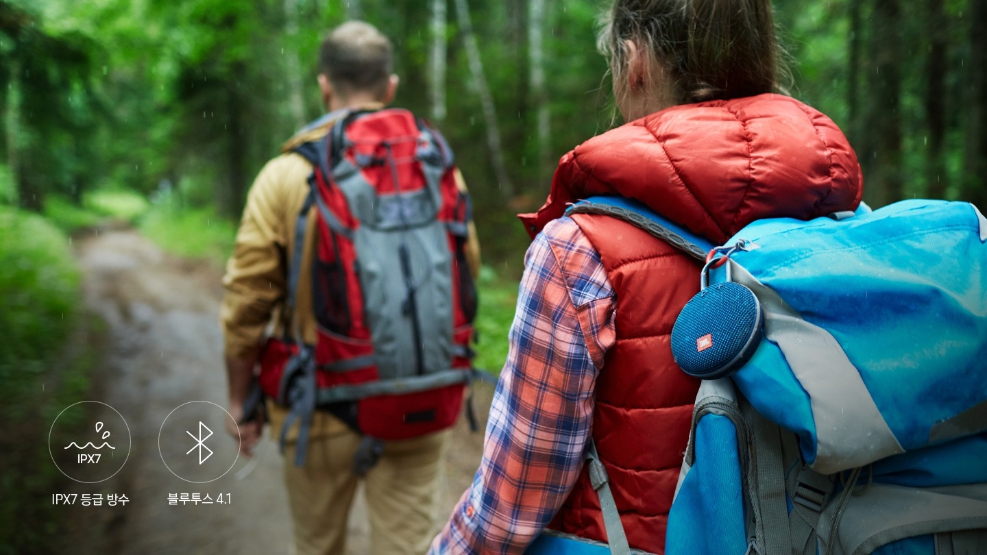등산을 하는 두명의 사람이 있으며, 여성의 배낭에 clip3를 달고 걸어가고 있습니다.