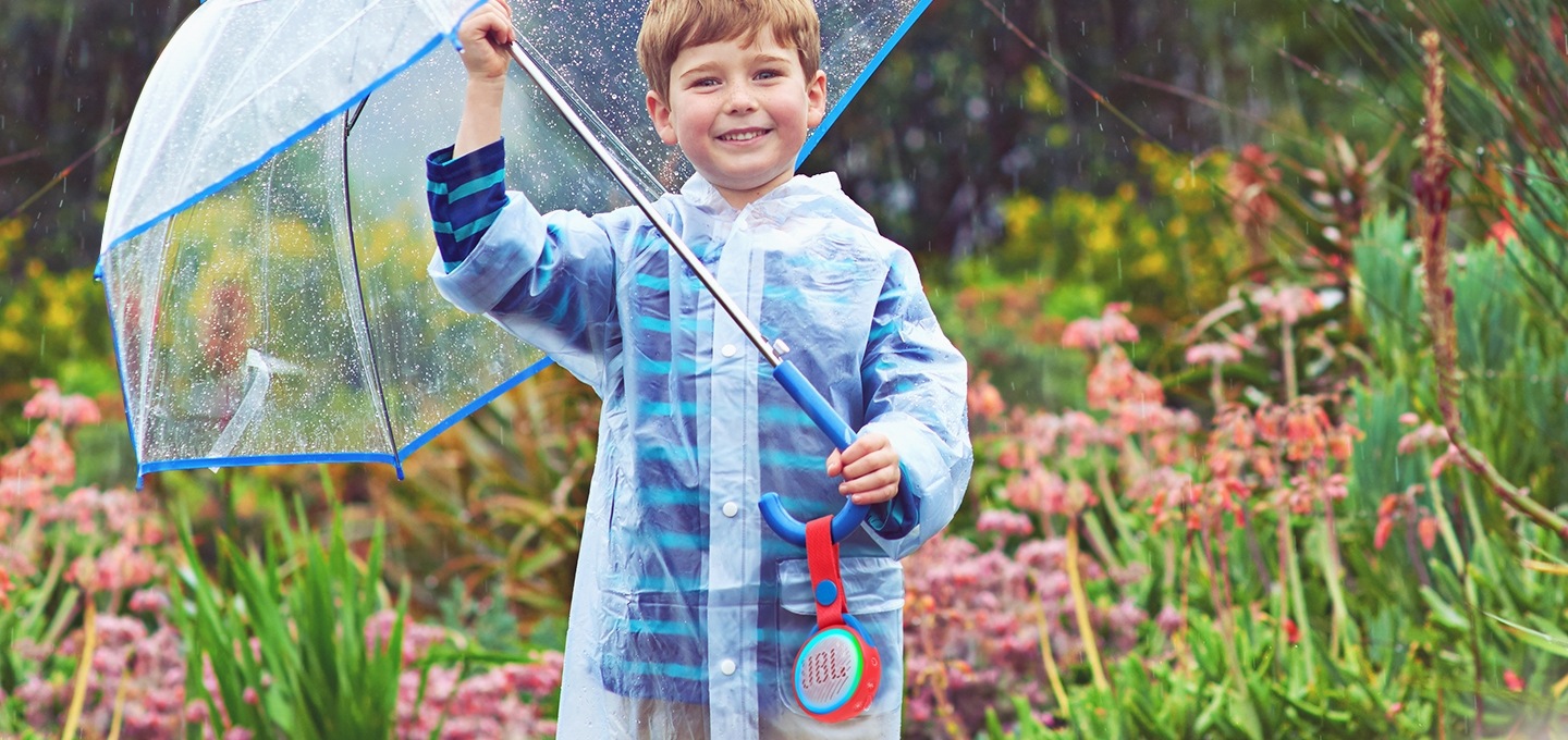 우산을 든 아이가 비속에서 제품을 소지한채 서 있습니다.