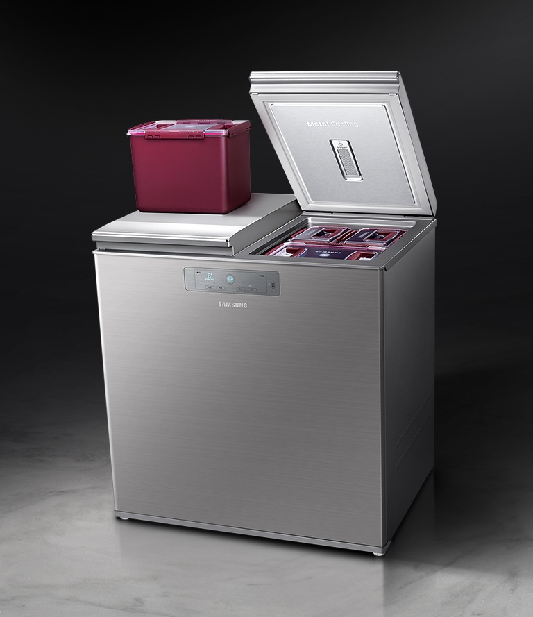 한쪽만 문이 열린 김치냉장고와 그 위에 올려진 김치통이 보여집니다.