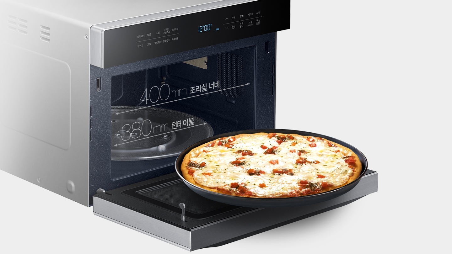 직화오븐 뚜껑이 열려있고 뚜껑위 큰 팬에 피자가 담겨있는 모습
