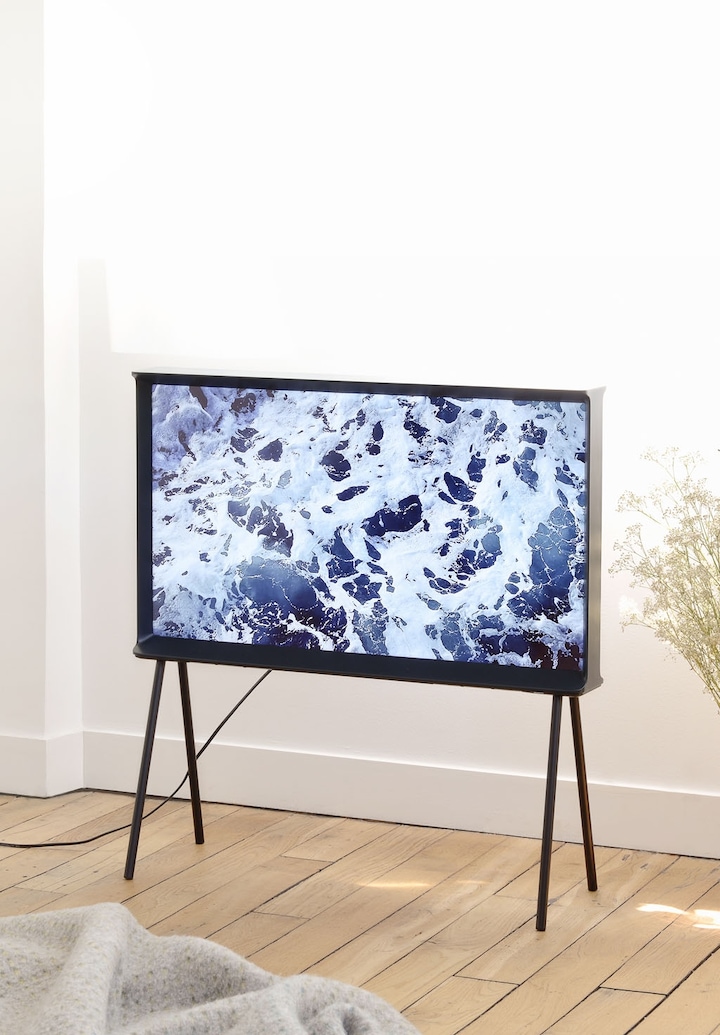 거실에 세리프 TV 다크 블루 컬러가 인테리어 되어 있는 모습이며 화면엔 파도 이미지가 보여지고 있습니다.