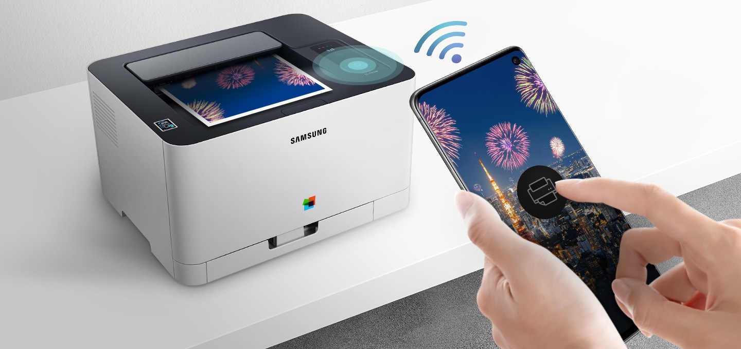 하얀색 책상 위에 제품을 오른쪽 위에서 내려본 이미지가 중간에 배치하여 있고 이미지 왼쪽 부분에 스마트폰 화면에 프린터 아이콘을 누르고 있는 사람의 손이 배치하여 있습니다.