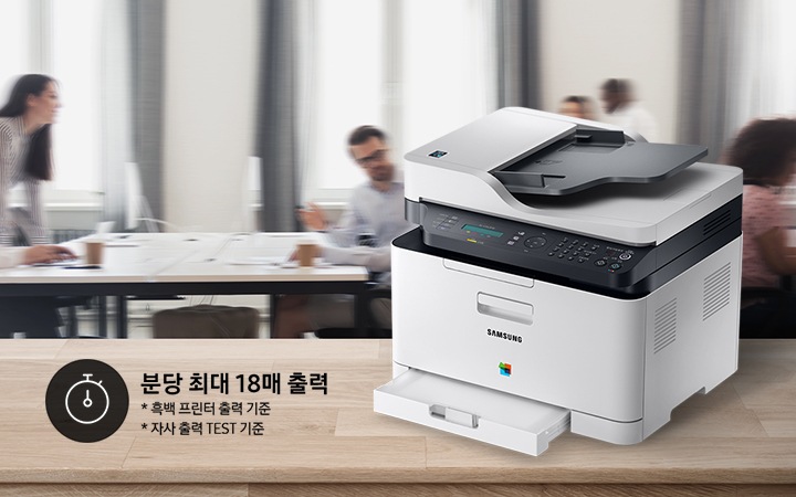 배경에는 바쁘게 회의를 하는 사람들의 모습, 바쁘게 지나가는 사람들의 모습이 흐릿하게 나와 있으며 이미지 오른쪽 부분에는 제품 오른쪽 위에서 내려본 이미지가 배치하여 있고이미지 왼쪽 하단에 분당 최대 18매 출력, * 흑백 프린터 출력 기준, 자사 출력 TEST 기준 텍스트가 쓰여 있으며, 타이머 아이콘이 나와있습니다.