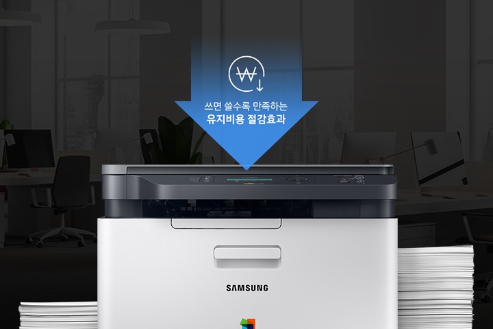 컬러 레이저복합기 18/4 ppm 화이트 제품 정면 모습과 주변에는 용지들이 쌓여있는 이미지 입니다. 상단에는 쓰면 쓸수록 만족하는 유지비용 절감효과라고 적혀있습니다.