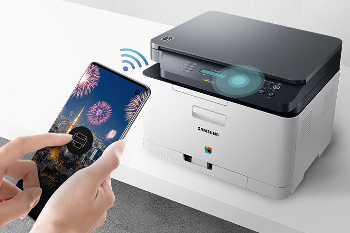 컬러 레이저복합기 18/4 ppm 화이트 제품이 화이트 책상위에 측면으로 놓여져 있고, 그 앞에 스마트폰이 있는 이미지 입니다. 스마트폰에 와이파이를 연결해 프린트를 할 수 있다는것을 알려주는 이미지 입니다.