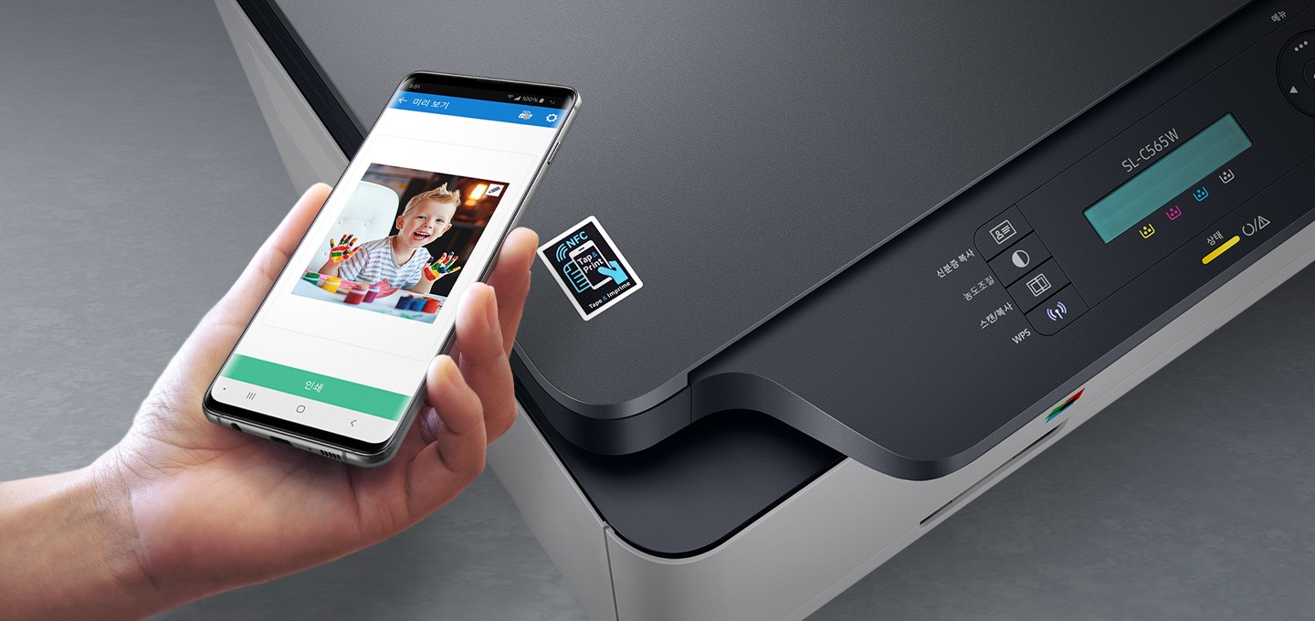 검정 색상의 나무 책상에 제품의 왼쪽 위에서 내려본 이미지가 있고 스마트폰을 제품 이미지 상단에 NFC 태그 스티커가 붙어있는 부분에 태그하는 이미지입니다.