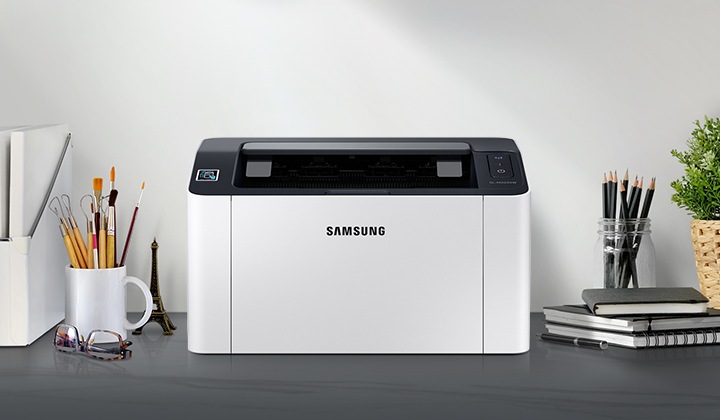 흑백 레이저프린터 20ppm 크림 화이트 제품 정면이 그레이 색상의 책상 위에 올려져 있고 주변에 사무용품들이 배치되어 있습니다.