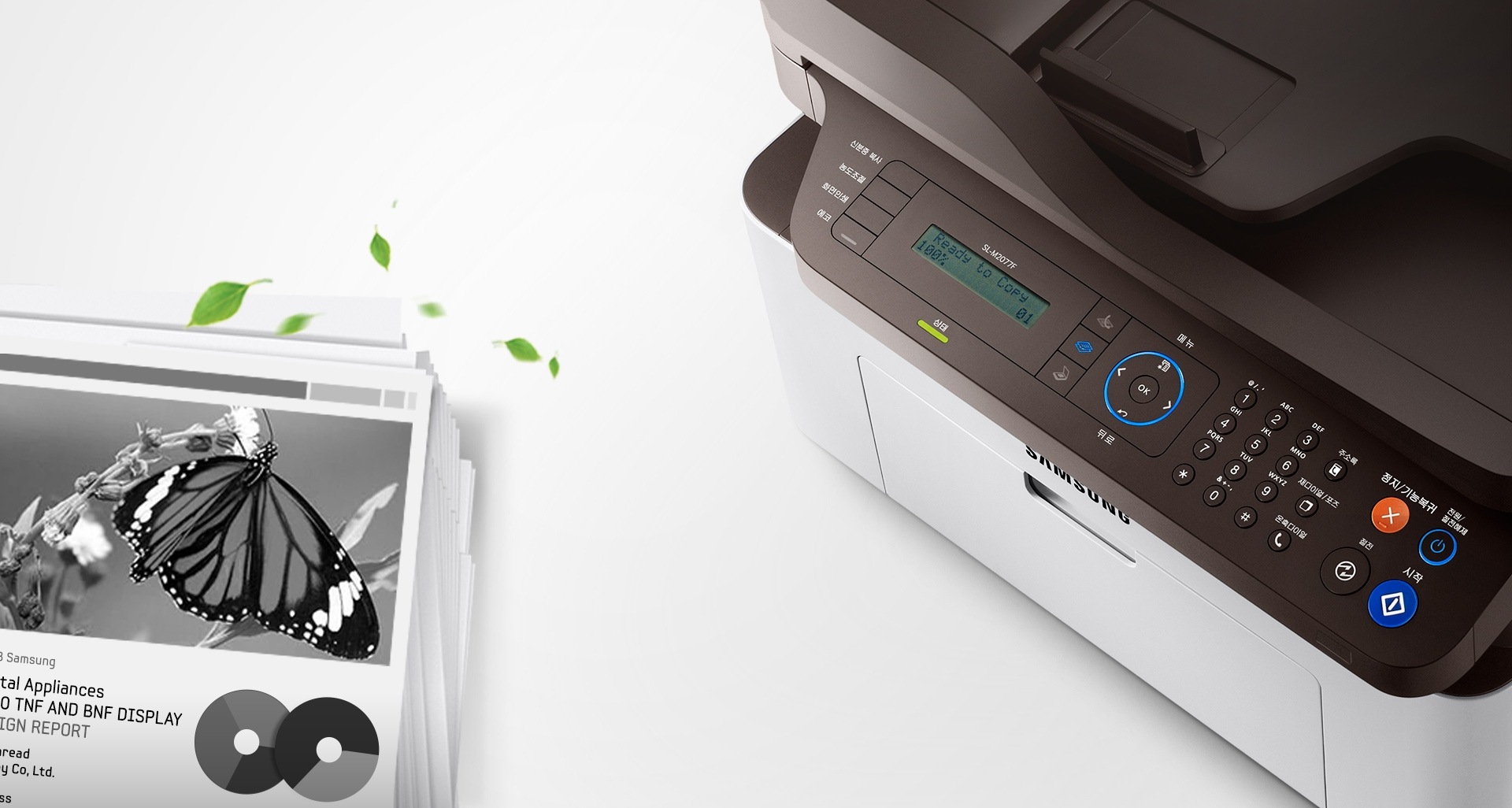 우측에 SL-M2077F 모델 있으며, 좌측에는 인쇄물이 놓여져 있다.