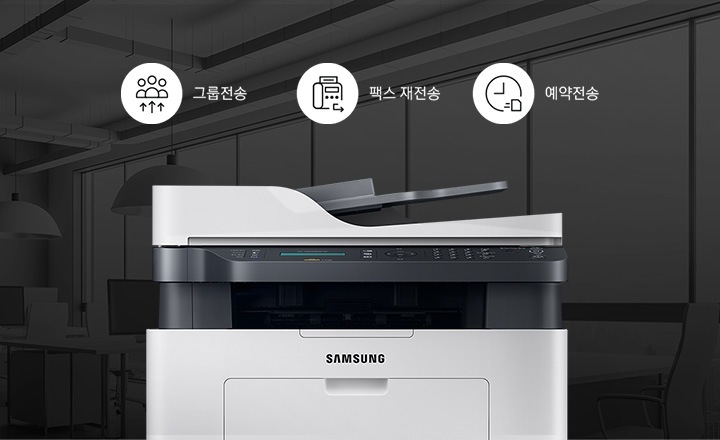 어두운 사무실 배경에 이미지 중간에는 제품 정면 이미지가 놓여있고 제품 이미지 상단에는 그룹전송 텍스트와 화살표가 위로 올라가며 사람을 가르키는 아이콘, 팩스 재전송 텍스트와 팩스 아이콘 오른쪽 하단에 되돌아가는 화살표 아이콘, 예약 전송 텍스트와 시계 아이콘이 왼쪽에서 오른쪽으로 나열되어 있습니다.