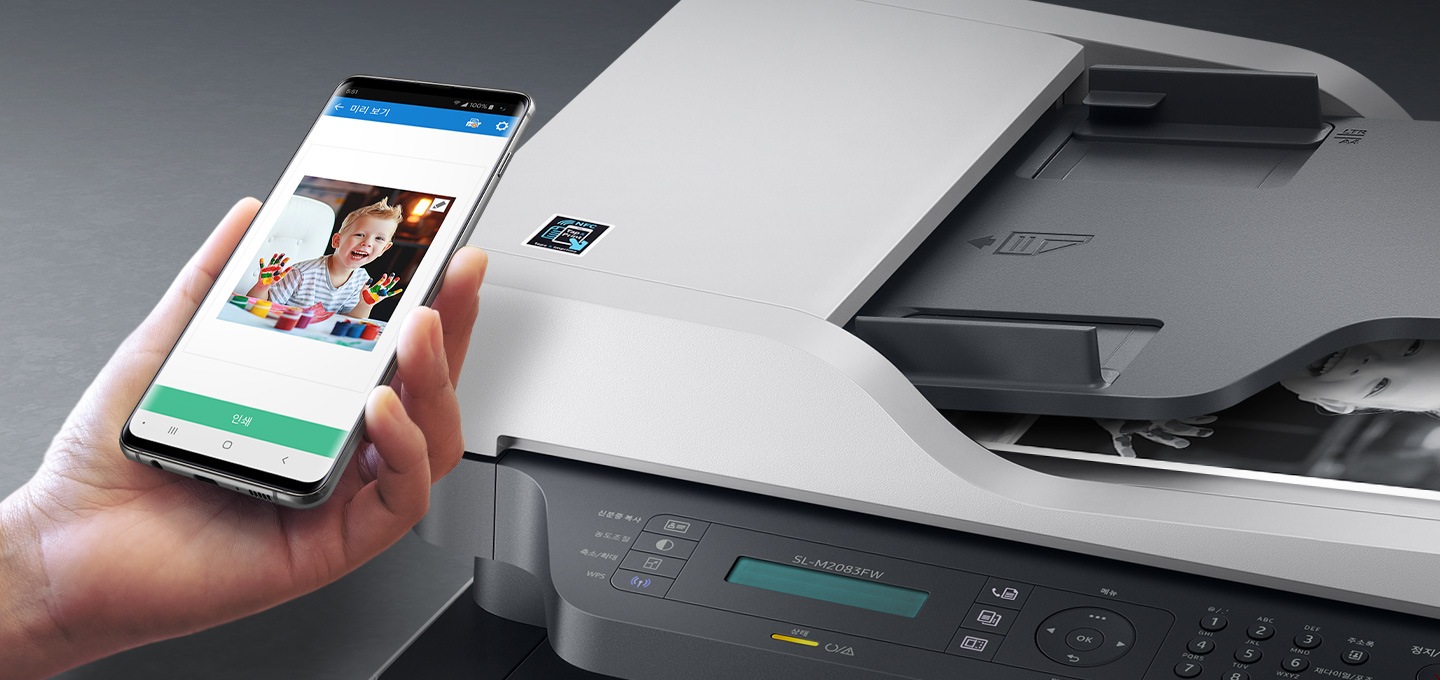 검정 색상의 나무 책상에 제품의 왼쪽 위에서 내려본 이미지가 있고 스마트폰을 제품 이미지 상단에 NFC 태그 스티커가 붙어있는 부분에 태그하는 이미지입니다.