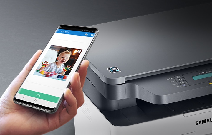 검정 색상의 나무 책상에 제품의 왼쪽 위에서 내려본 이미지가 있고 스마트폰을 제품 이미지 상단에 NFC 태그 스티커가 붙어있는 부분에 태그하는 이미지입니다.