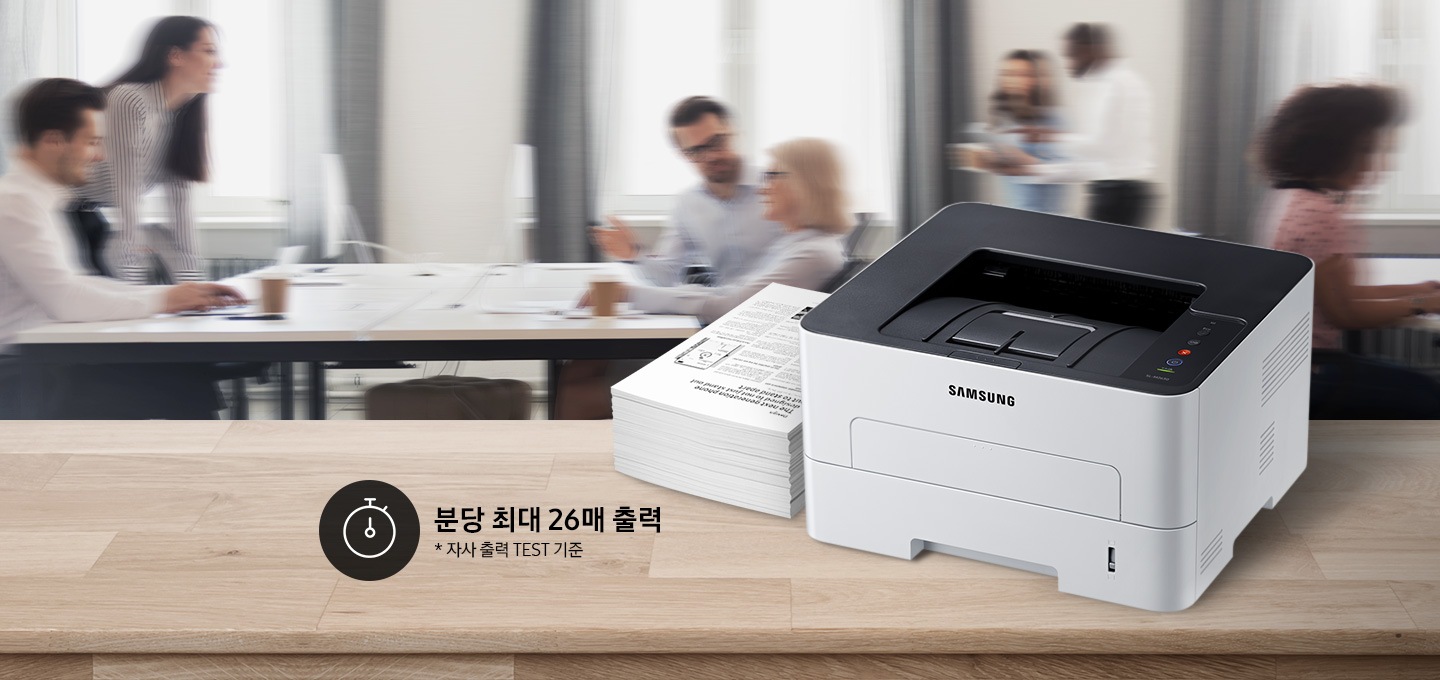 배경에는 바쁘게 회의를 하는 사람들의 모습, 바쁘게 지나가는 사람들의 모습이 흐릿하게 나와 있으며 이미지 오른쪽 부분에는 제품 오른쪽 위에서 내려본 이미지가 배치하여 있고이미지 왼쪽 하단에 분당 최대 26매 출력, 자사 출력 TEST 기준 텍스트가 쓰여 있으며, 타이머 아이콘이 나와있습니다.