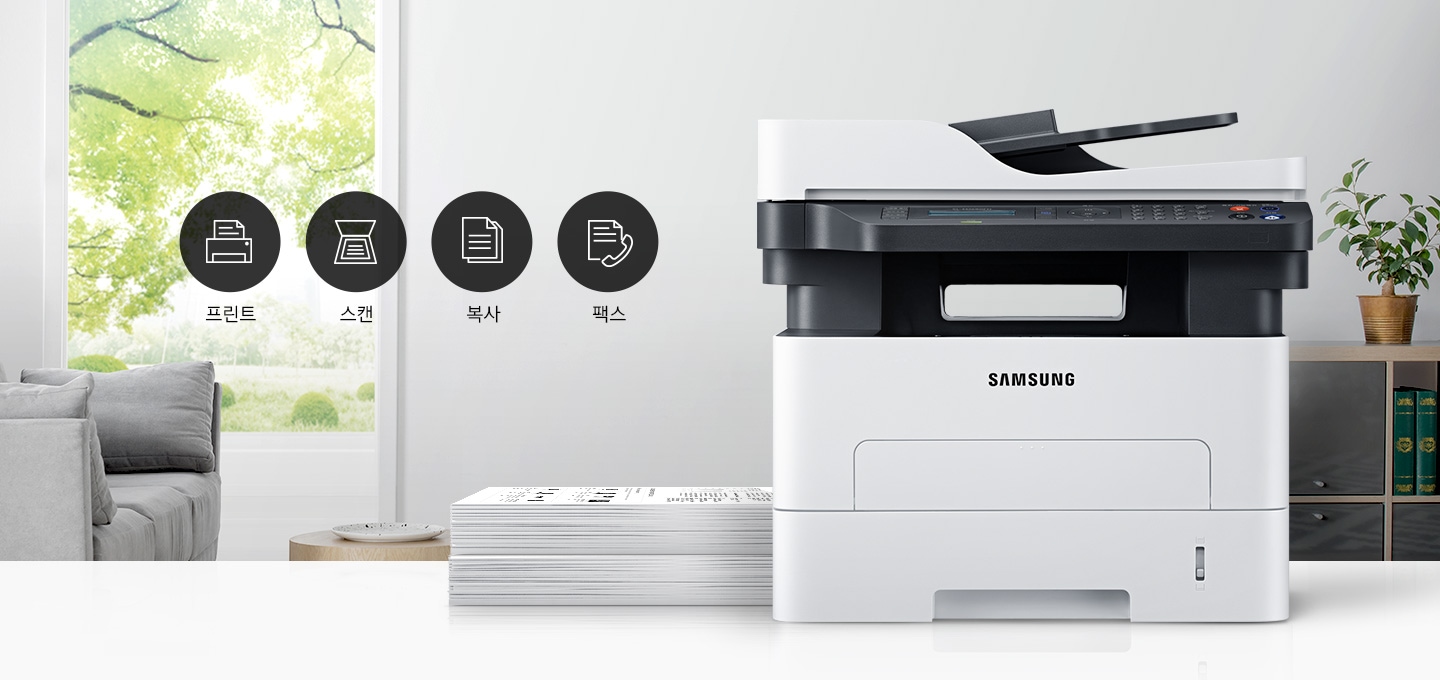 이미지 왼쪽에는 푸른 나무가 보이는 창문과 회색 소파가 배치되어 있으며, 이미지 오른쪽에는 제품 정면 이미지가 배치되어 있습니다. 제품 이미지 왼쪽에는 종이가 쌓여 있으며, 제품 이미지와 소파 사이에는 프린터 텍스트와 프린터 아이콘, 스캔 텍스트와 스캔 아이콘, 복사 텍스트와 복사 아이콘, 팩스 텍스트와 팩스 아이콘이 왼쪽에서 오른쪽으로 나열하여 있습니다.