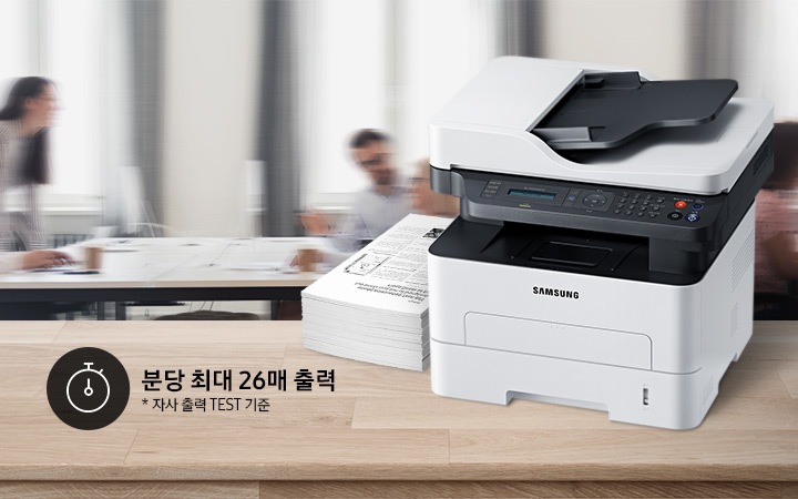배경에는 바쁘게 회의를 하는 사람들의 모습, 바쁘게 지나가는 사람들의 모습이 흐릿하게 나와 있으며 이미지 오른쪽 부분에는 제품 오른쪽 위에서 내려본 이미지가 배치하여 있고이미지 왼쪽 하단에 분당 최대 26매 출력, 자사 출력 TEST 기준 텍스트가 쓰여 있으며, 타이머 아이콘이 나와있습니다.