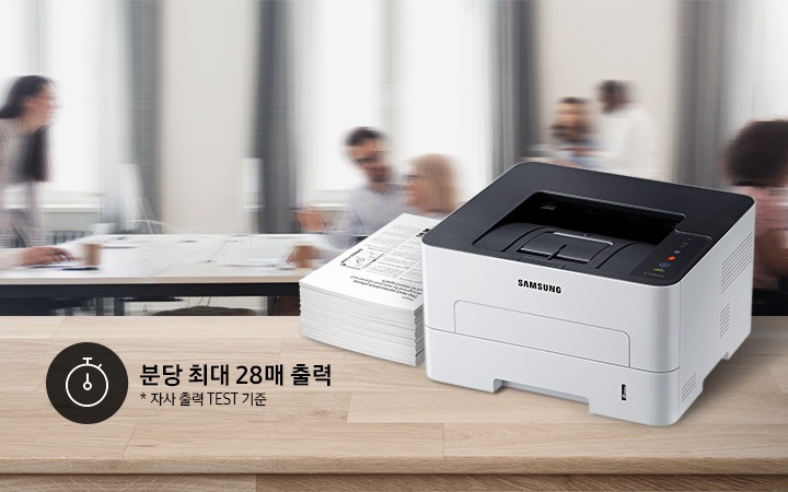 배경에는 바쁘게 회의를 하는 사람들의 모습, 바쁘게 지나가는 사람들의 모습이 흐릿하게 나와 있으며 이미지 오른쪽 부분에는 제품 오른쪽 위에서 내려본 이미지가 배치하여 있고이미지 왼쪽 하단에 분당 최대 28매 출력, 자사 출력 TEST 기준 텍스트가 쓰여 있으며, 타이머 아이콘이 나와있습니다.