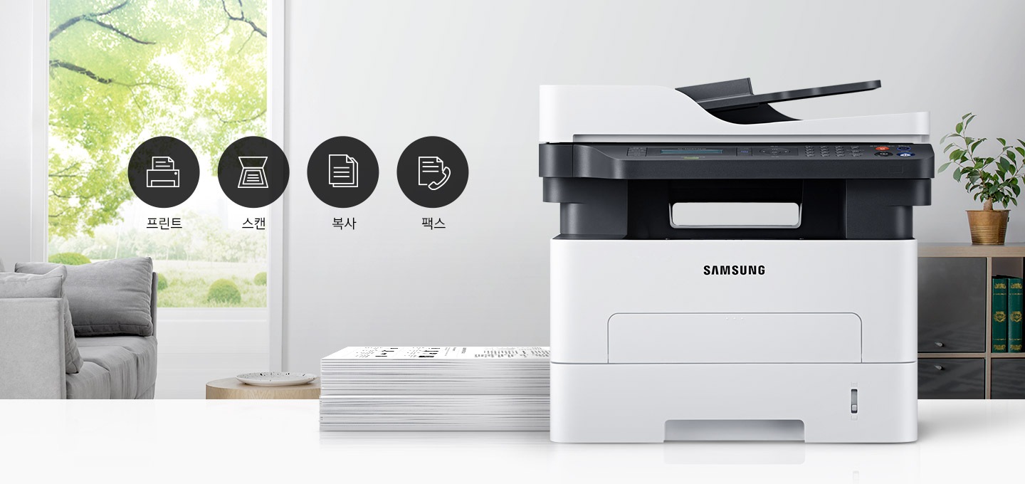 이미지 왼쪽에는 푸른 나무가 보이는 창문과 회색 소파가 배치되어 있으며, 이미지 오른쪽에는 제품 정면 이미지가 배치되어 있습니다. 제품 이미지 왼쪽에는 종이가 쌓여 있으며, 제품 이미지와 소파 사이에는 프린터 텍스트와 프린터 아이콘, 스캔 텍스트와 스캔 아이콘, 복사 텍스트와 복사 아이콘, 팩스 텍스트와 팩스 아이콘이 왼쪽에서 오른쪽으로 나열하여 있습니다.